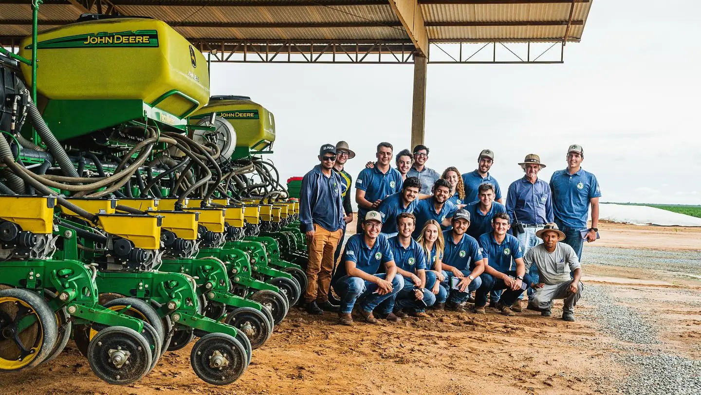 Equipe e visitantes ao lado das plantadeiras, no galpão da fazenda